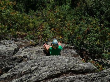 Rear view of man sitting on rock