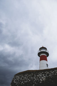 Low angle view of lighthouse by building against sky