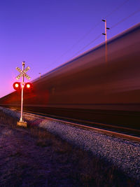 Illuminated railroad tracks by speeding train against clear sky