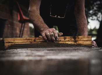 Midsection of worker flattening cement on floor at construction site