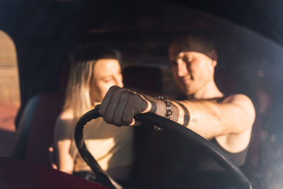 Cool boyfriend sitting in car with cool girlfriend on sunny day