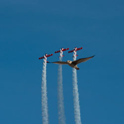 Low angle view of airplane flying against clear blue sky