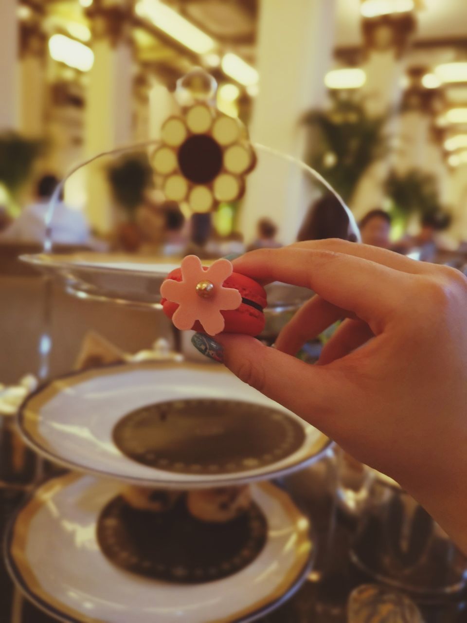 CLOSE-UP OF HAND HOLDING COFFEE CUP AND SPOON ON TABLE