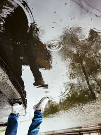 Low section of man standing on puddle