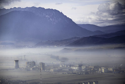 Buildings against mountains during foggy weather