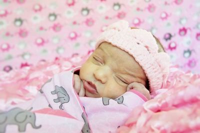 Close-up of newborn baby girl wrapped in blanket sleeping at home