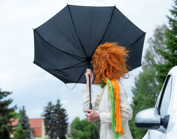 Woman holding umbrella while standing outdoors