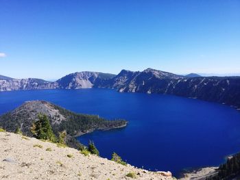 Scenic view of lake and mountains against clear blue sky