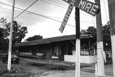 Road sign by built structure against sky