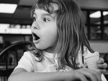 Cute surprised girl holding ice cream at restaurant