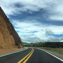 Road by mountains against sky