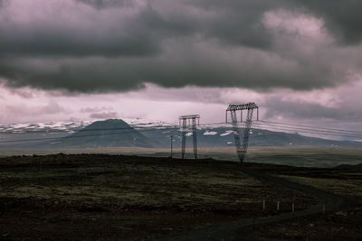 Electricity pylon on field against sky