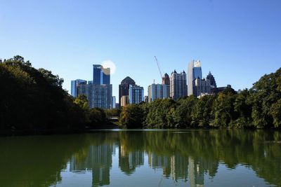 Reflection of buildings in lake against clear sky