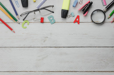 Directly above shot of letters with eyeglasses and pencils on wooden table