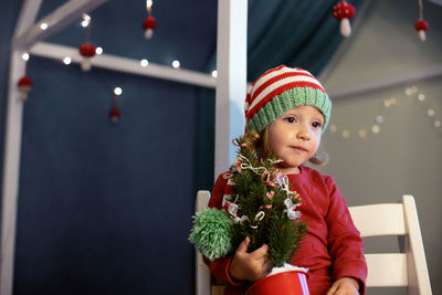 Portrait of smiling young woman holding christmas tree