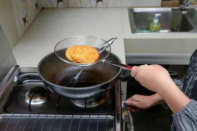 Cropped hand of man preparing food in kitchen