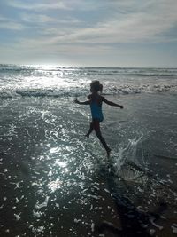 Boy running on beach against sky