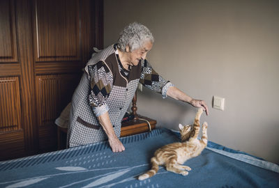 Senior woman playing with her cat at home