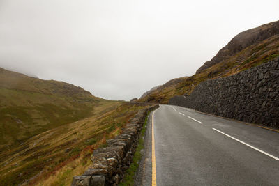 Road passing through mountain against sky