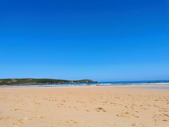 Scenic view of beach against clear blue sky
