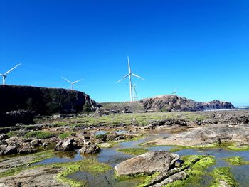Wind turbines on landscape against blue sky