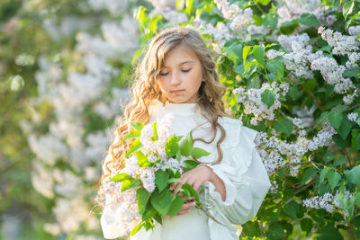 Low angle view of girl standing on flowering plant