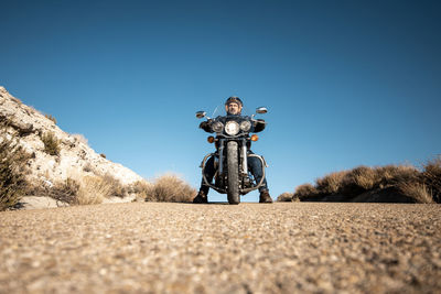 Low angle view of man standing on land against clear sky