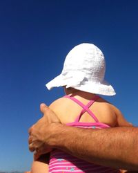 Low angle view of woman standing against blue sky