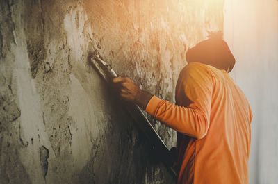 Side view of man standing against wall