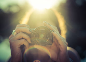 Close-up of woman holding camera on sunny day