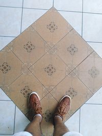 Low section of man standing on tiled floor