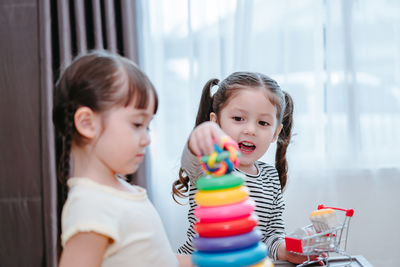 Sisters playing with multi colored toys at home