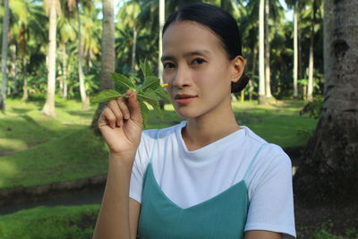 Portrait of young woman holding plant