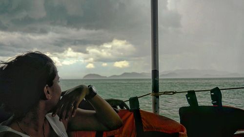 People on boat in sea against cloudy sky