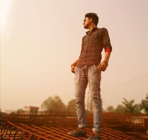 Low angle view of young man standing on metallic rods at construction site