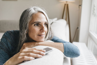 Smiling woman sitting on the couch looking through window