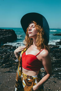 Young woman wearing hat while standing on beach