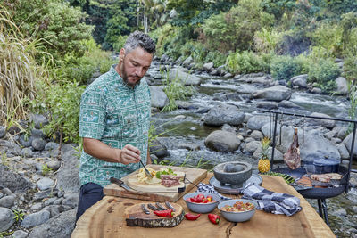 Chef preparing campsite picnic with woodfire grill and appetizers