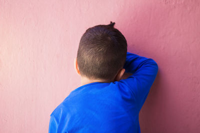 Rear view of boy standing against wall