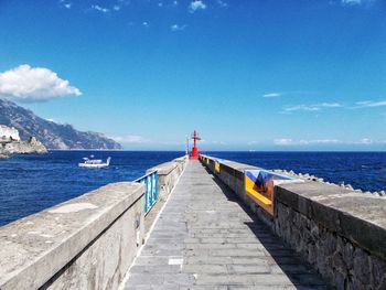 Pier on sea against cloudy sky