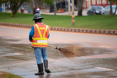 Rear view of worker cleaning road