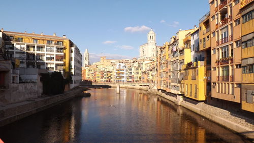 Canal in city against sky