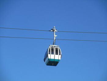 Low angle view of overhead cable car against clear blue sky