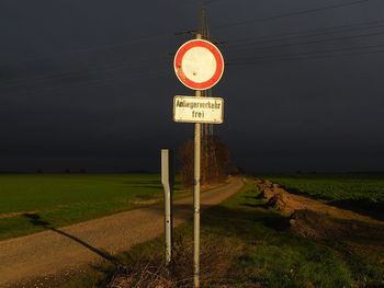 Information sign on road by field against sky