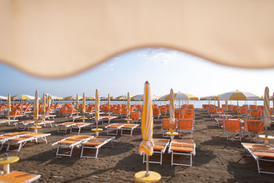 Empty chairs and tables at beach against clear sky
