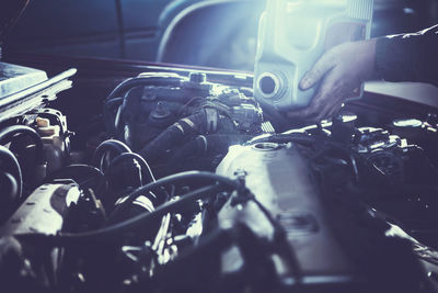 Cropped hands of mechanic repairing engine in workshop