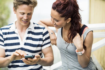 Mid adult couple using mobile phone outdoors