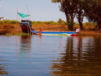 People in boat by river against sky