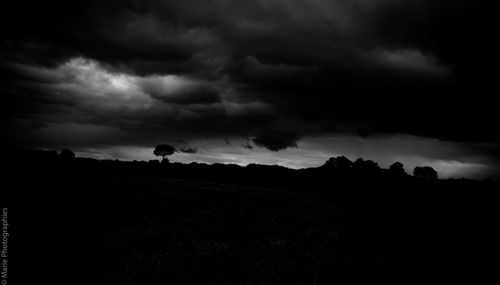 Silhouette of field against storm clouds