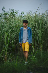 Young man walking on grassy field against sky